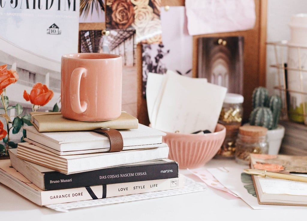 Desk with a pile of books and a mug on top