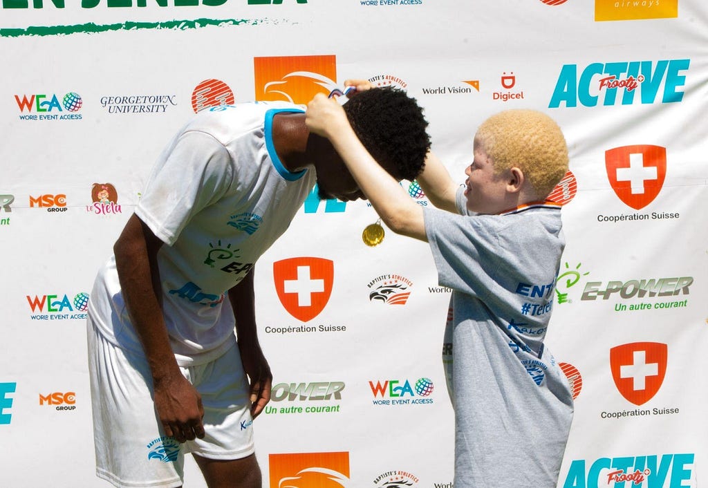 A boy leans so that another youth can place a medal around his neck.