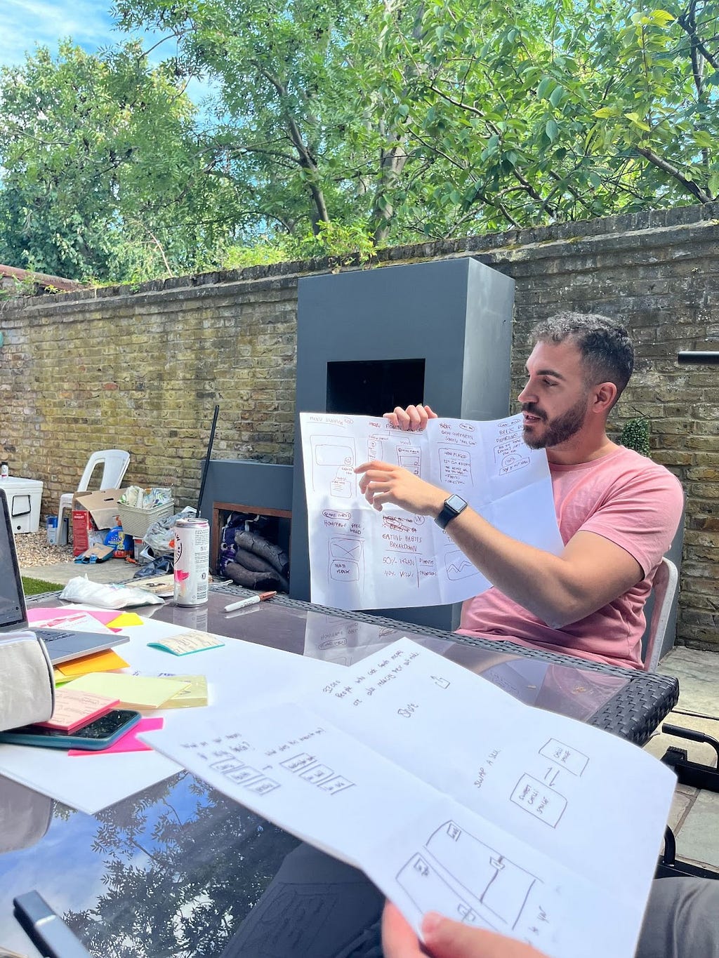 Man in pink shirt holding up paper and describing his sketch