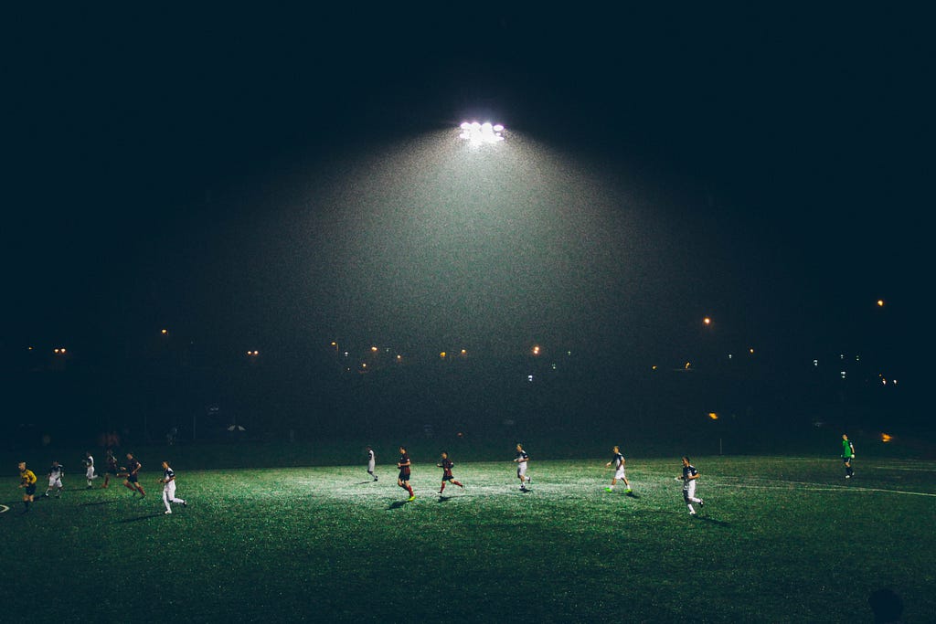 Soccer field at night time with players running