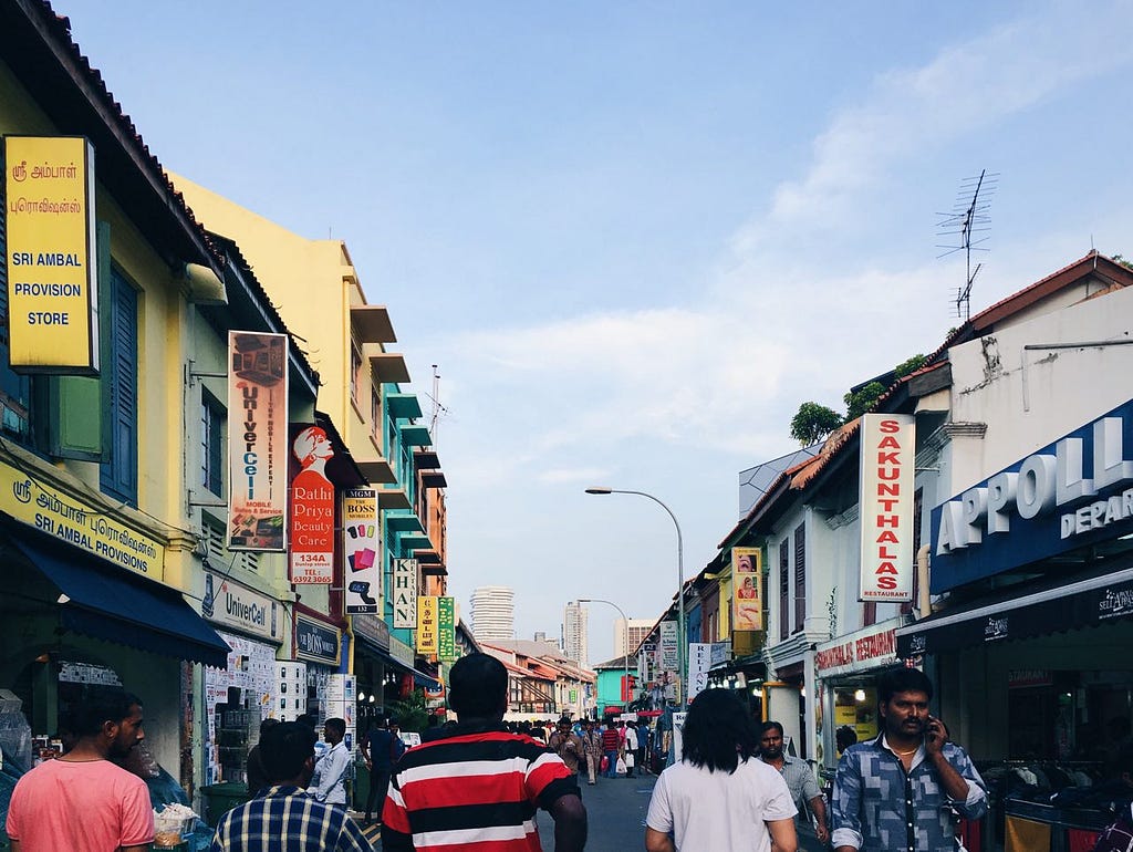 A view of one of street in Little India, with blue skies and shophouses on both sides