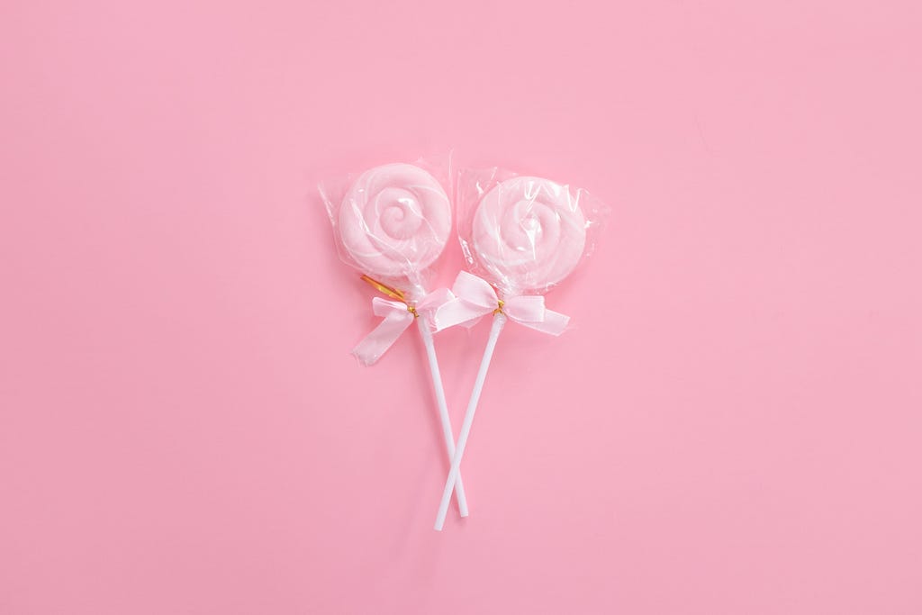Two pink lollipops against a pink background.