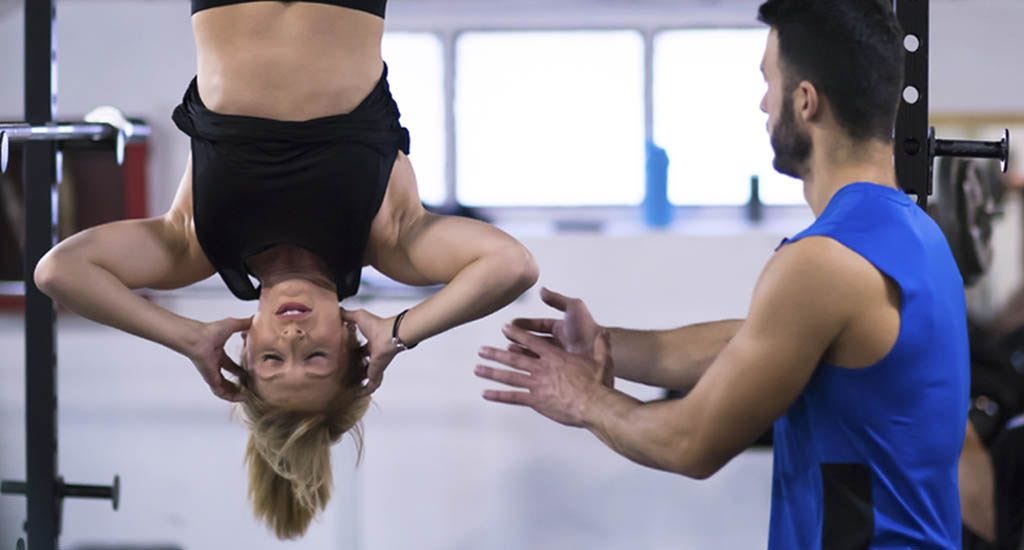 Woman doing abs exercises upside down with personal trainer