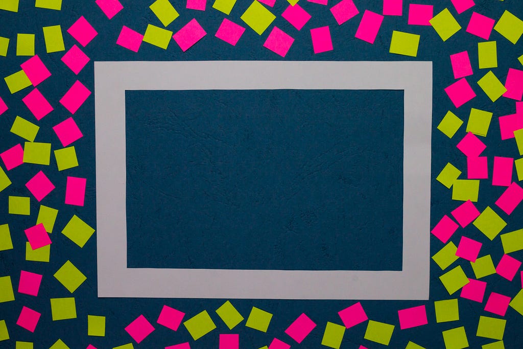 A blank picture frame on a dark background, surrounded by yellow and pink sticky notes