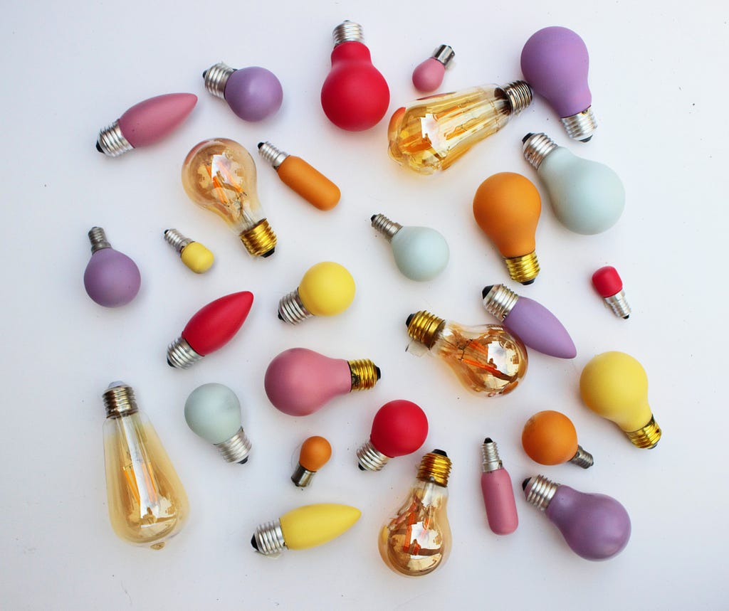 Lightbulbs of many colors lying on a surface.