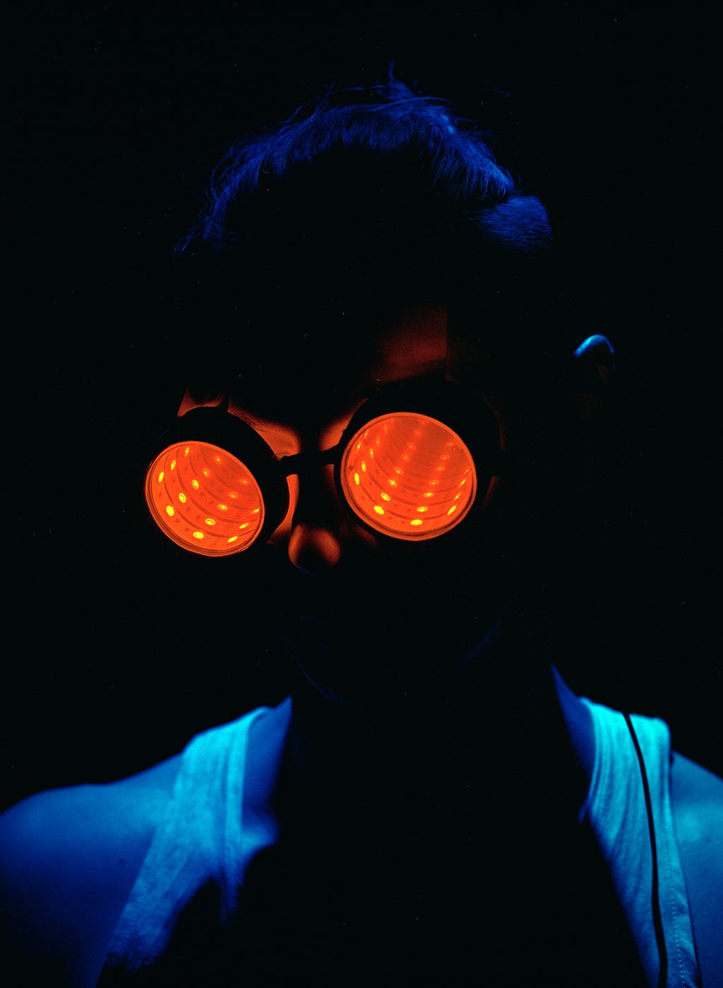 a dark picture of a man wearing red futuristic spectacles