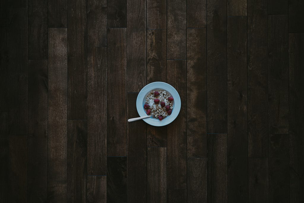 A small bowl of cereal on dark wood floors