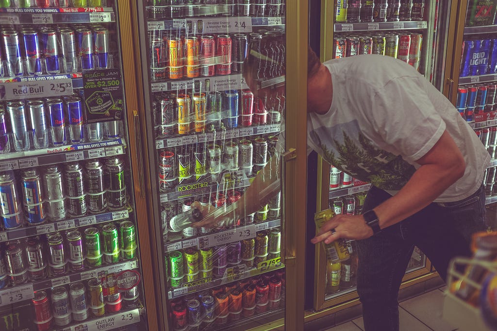 Man opening refridgerator door to grab energy drink