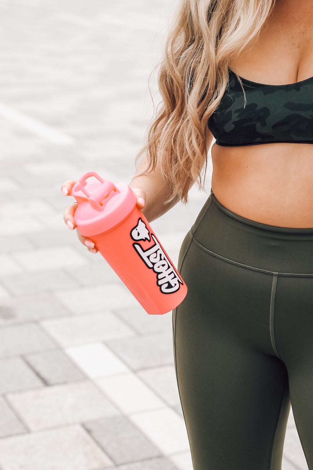 A picture of a young woman holding a protein shaker bottle
