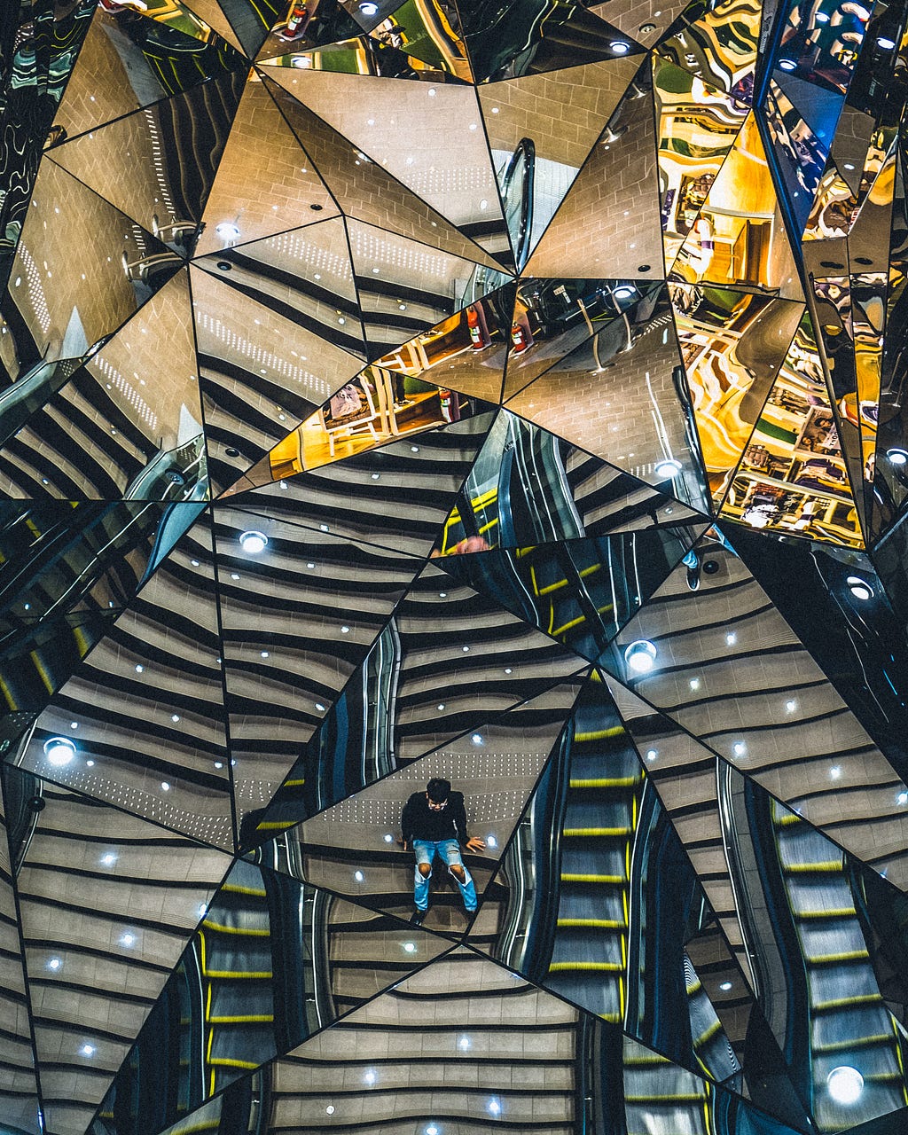 A lot of triangle shaped mirrors together reflecting the view.