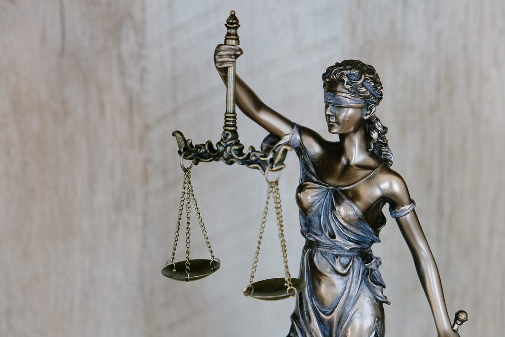 Lady Justice holding a balanced scale with a blindfold.