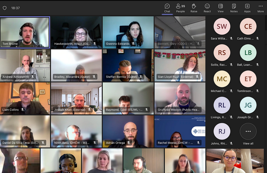 A Microsoft Teams video call interface showing multiple participants in a grid layout. The call has 35 participants, with some visible as video feeds and others as initials in colored circles. Various controls like Chat, Raise Hand, and React are visible at the top of the screen. The time shown is 18:37.