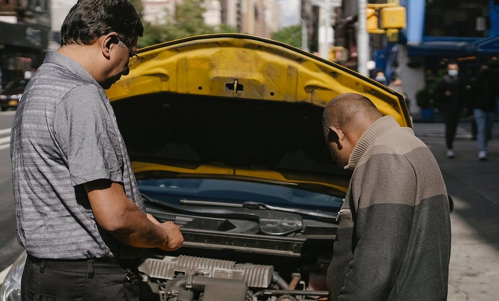 Men attempting to fix a car.