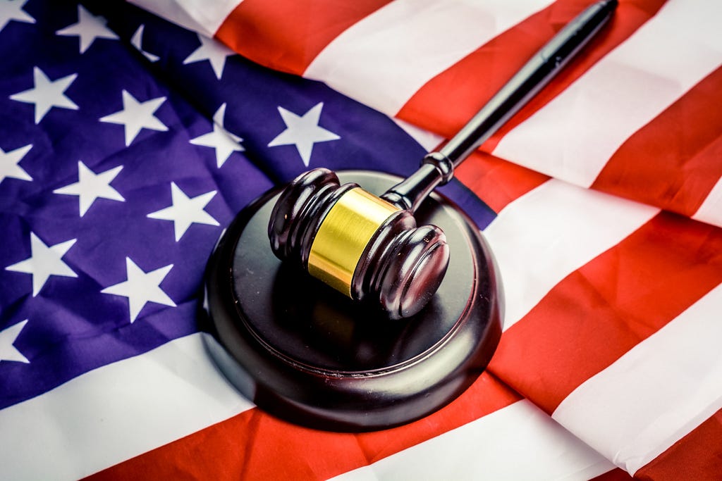 A gavel and sound block with the flag of the United States underneath.