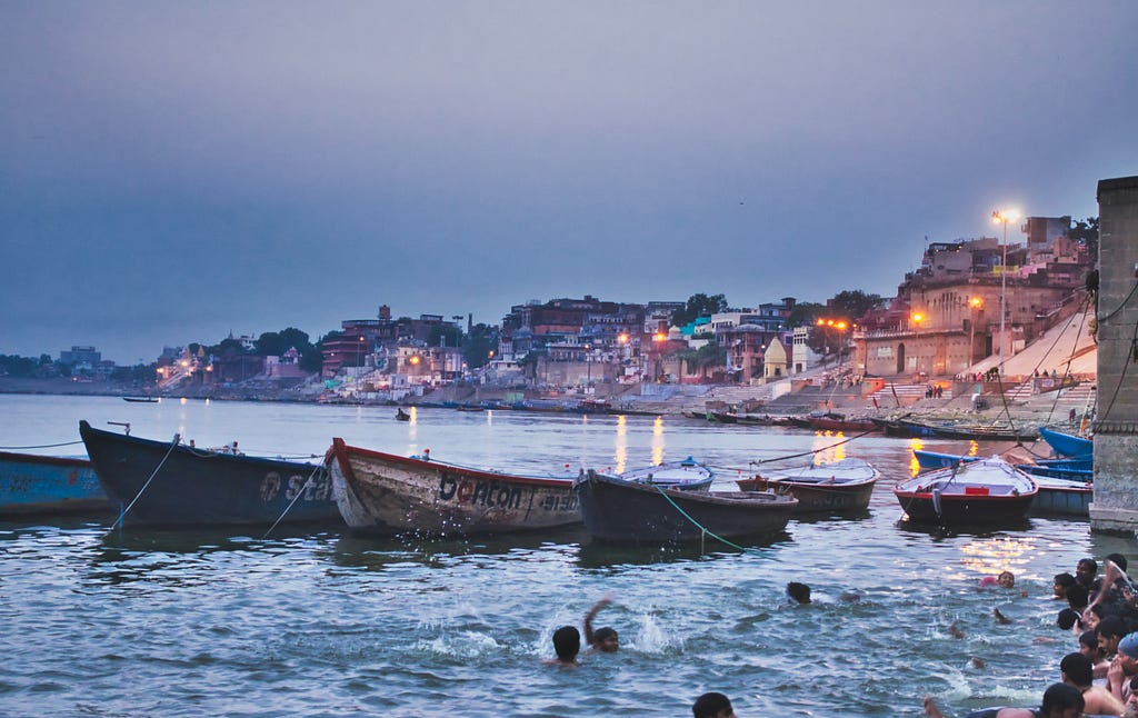 banaras ghat, boats are parked and children are swimming