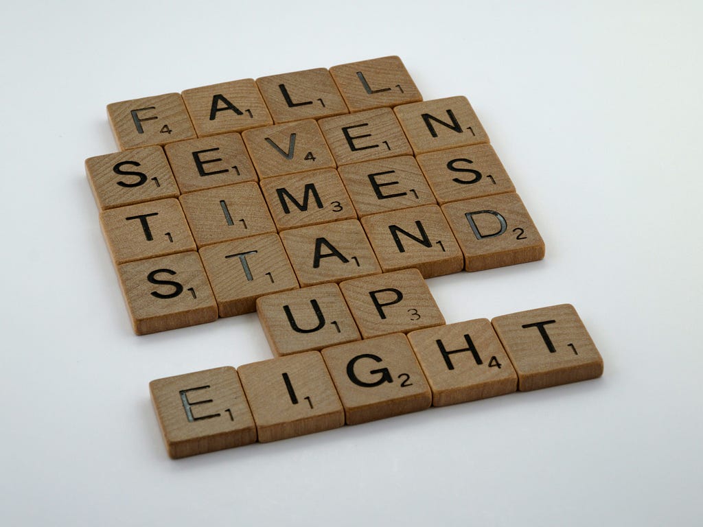 This image depicts scrabble pieces that spell out “Fall,” “Seven,” “Times,” “Stand,” “Up,” and “Eight.”