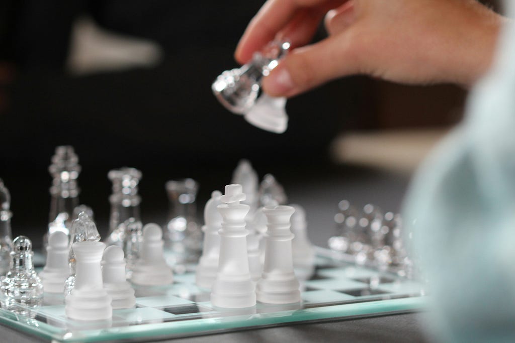 The player is holding two chess pieces in his hand while making a move.