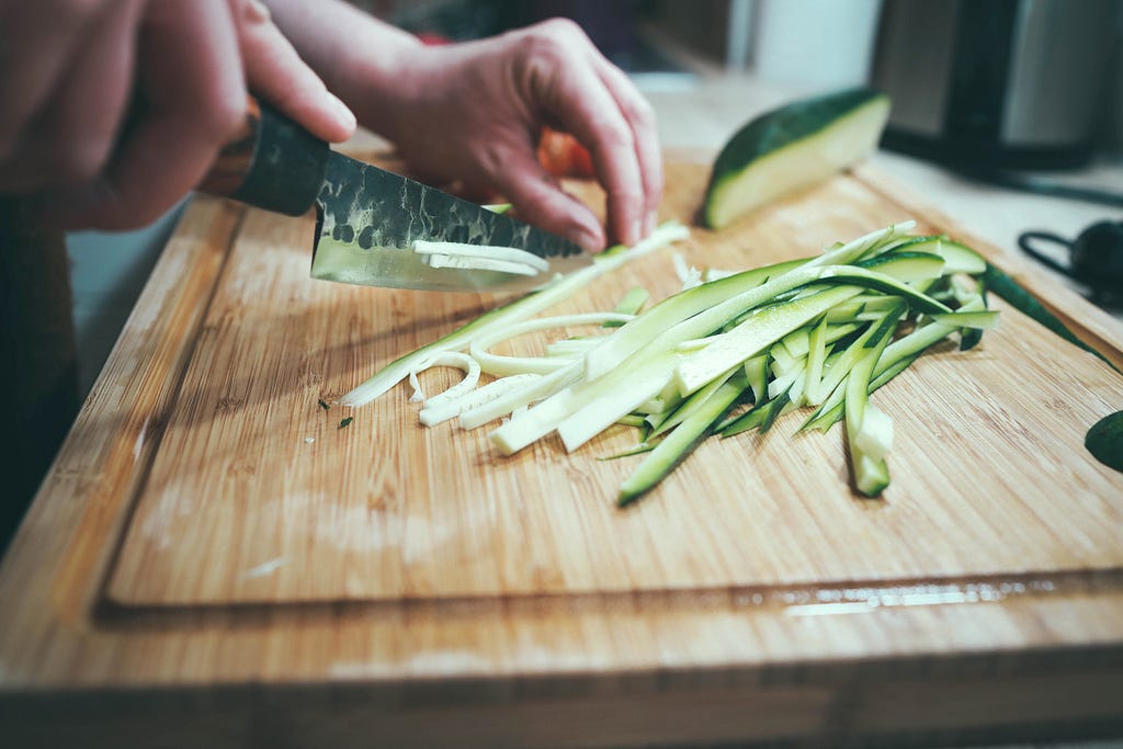 Strips of freshly-cut cucumber on a cutting board.