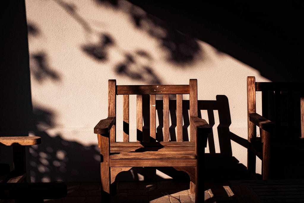 Empty chair against a beige wall with evening shadows