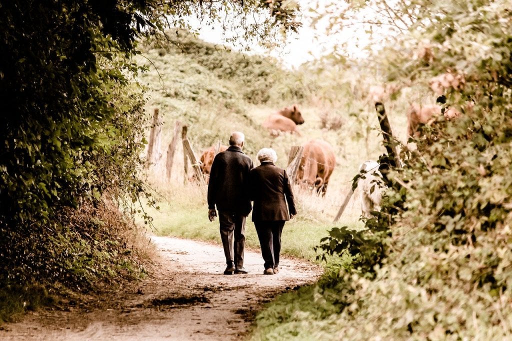 an old couple walking through a ranch