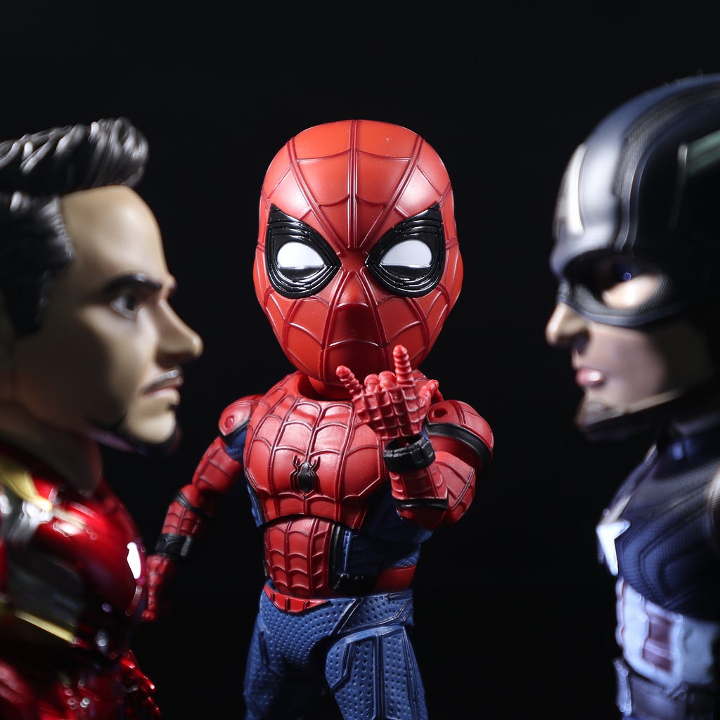 Toy figurines of Iron Man, Spider an and Captain America staring intently at each other.