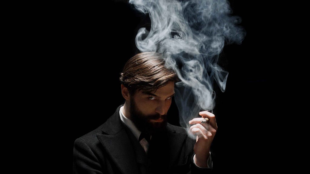 Actor Robert Finster as Sigmund Freud. He broods against a black background, with a cloud of smoke rising from his cigarette.