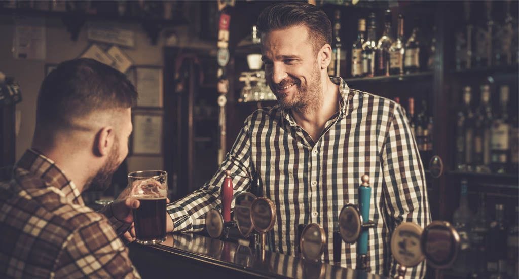 Working bartender serving alcohol at bar