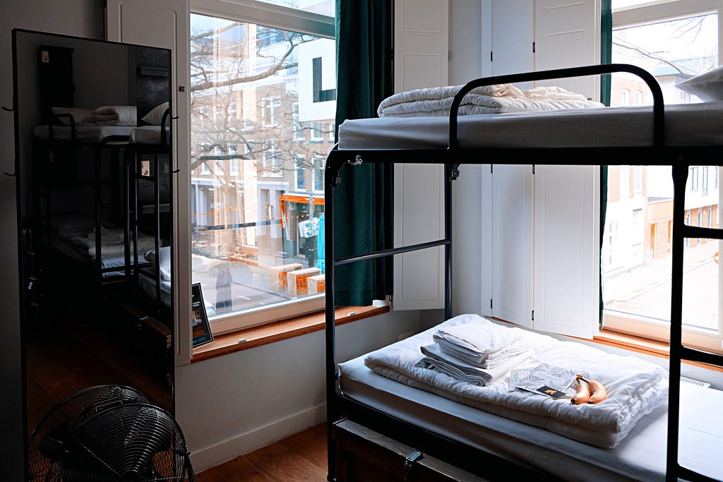 Bunk beds sit in the corner of a simple hostel room.