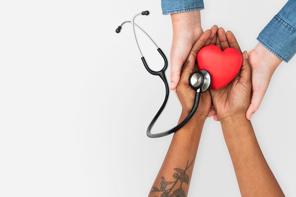 2 people holding stethoscope and a dummy heart.