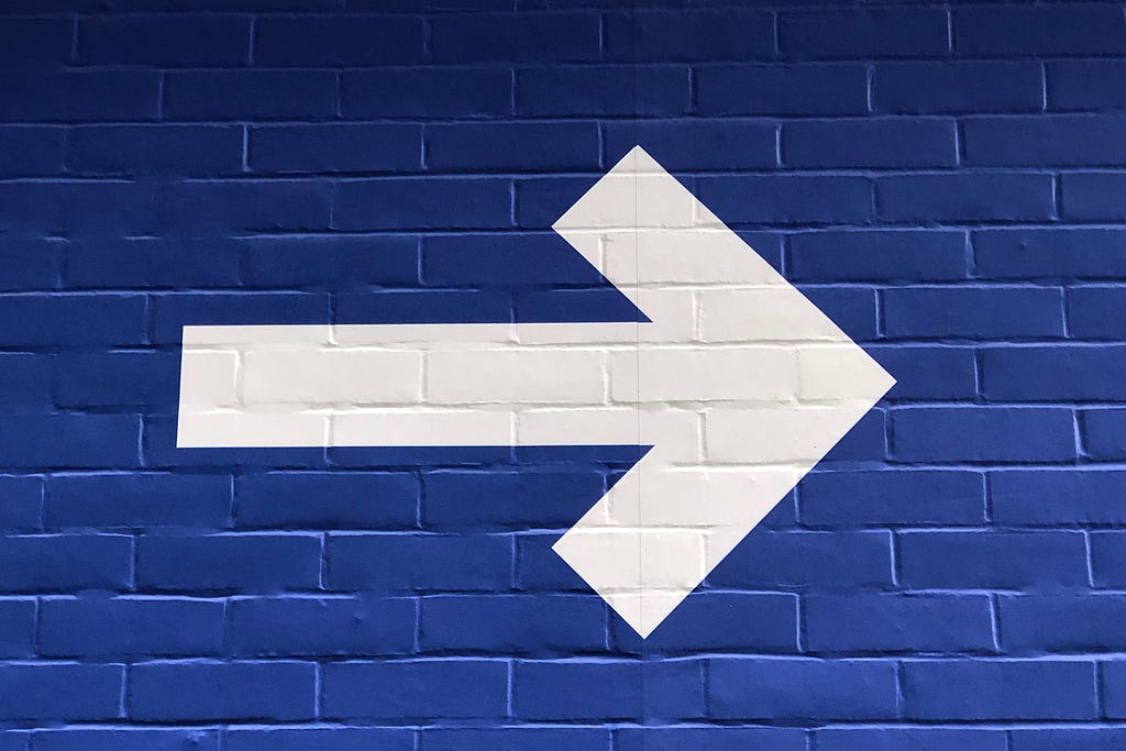 A photo of a large arrow painted on a wall. The arrow is pointing to the right.