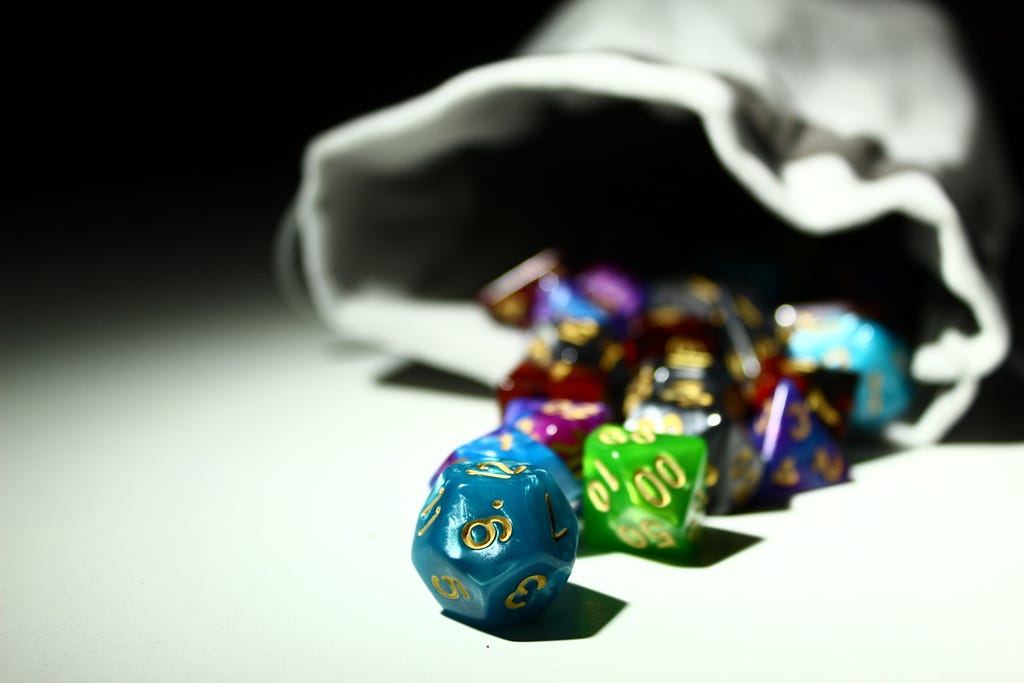 A lot of colorful Dungeons and Dragons dice falling out of a bag of dice.