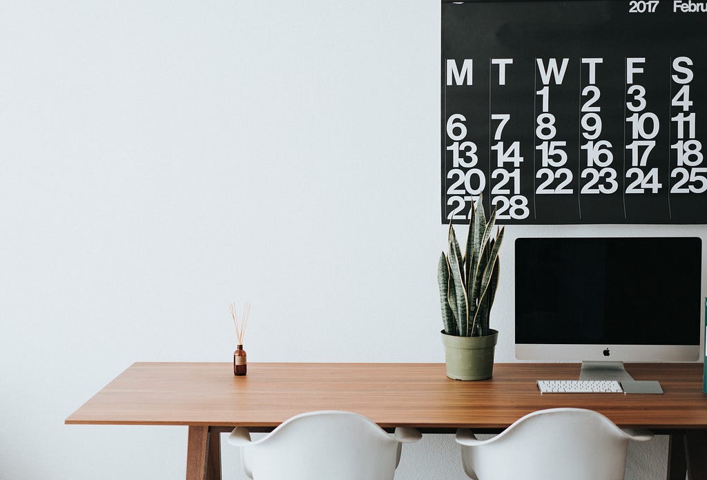 A plant on a wooden table with calendar for productivity