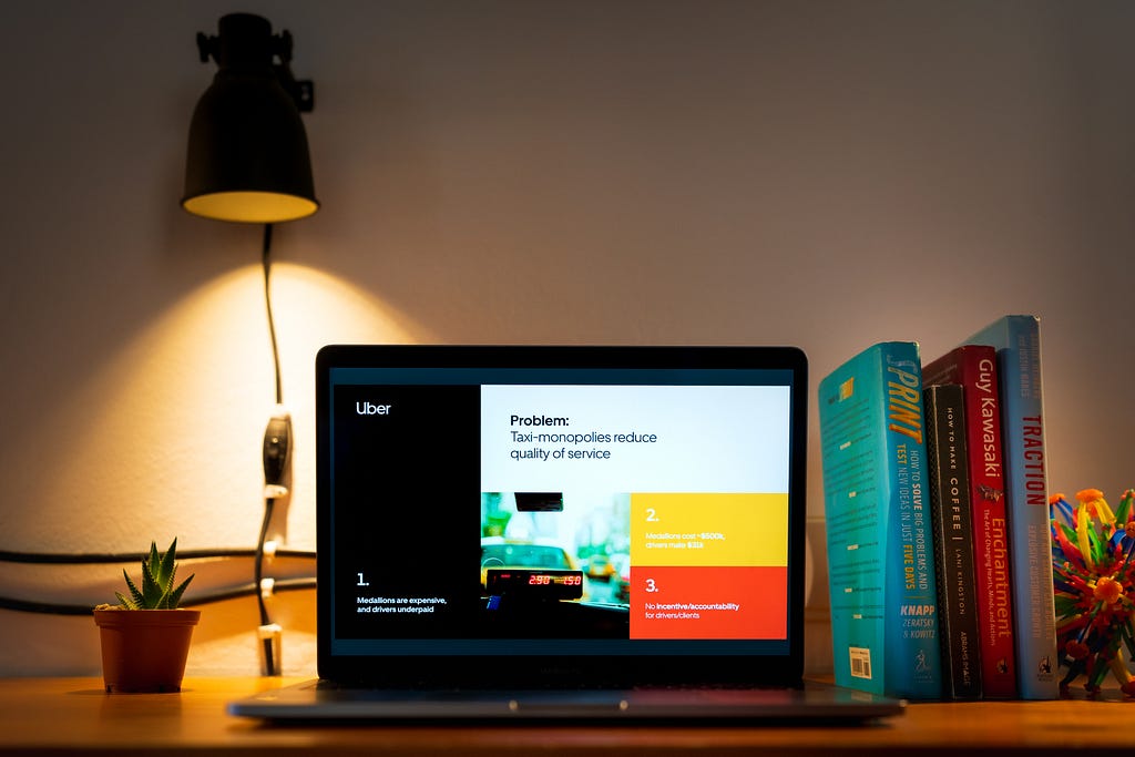 Um notebook em cima de uma escrivaninha mostrando uma apresentação sobre o problema que o serviço da Uber resolve.
