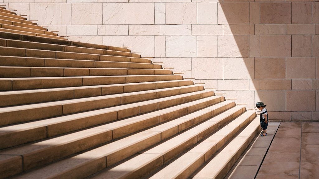 A small boy looking at a large set of stairs in front of him