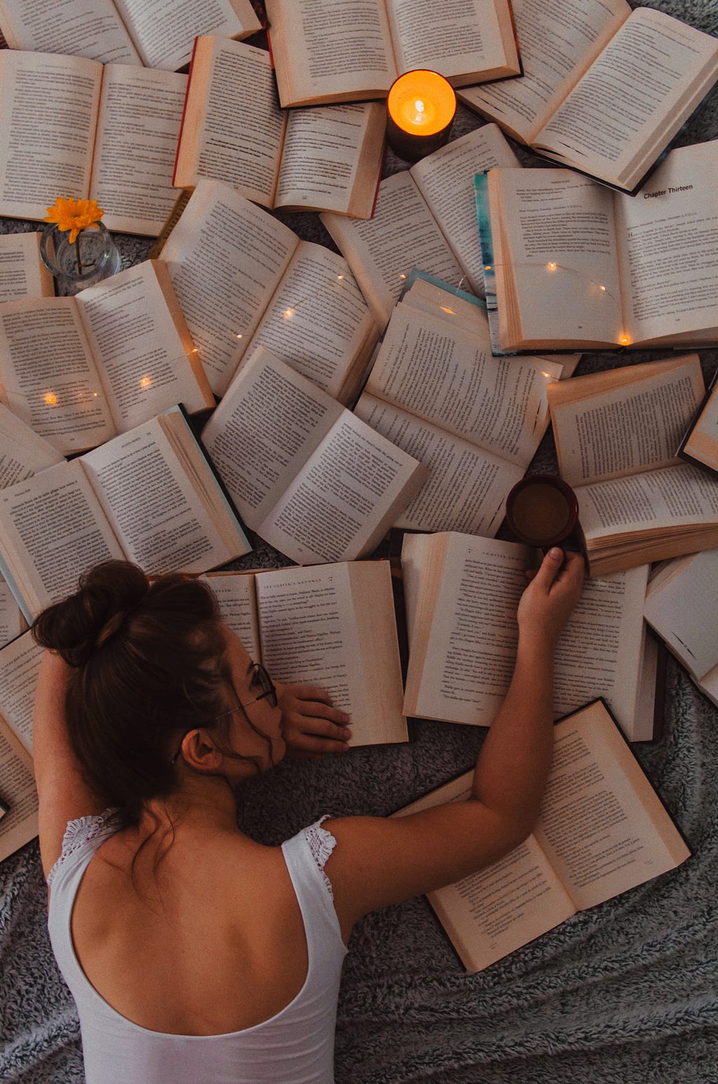 A girl lying on a pile of open books.