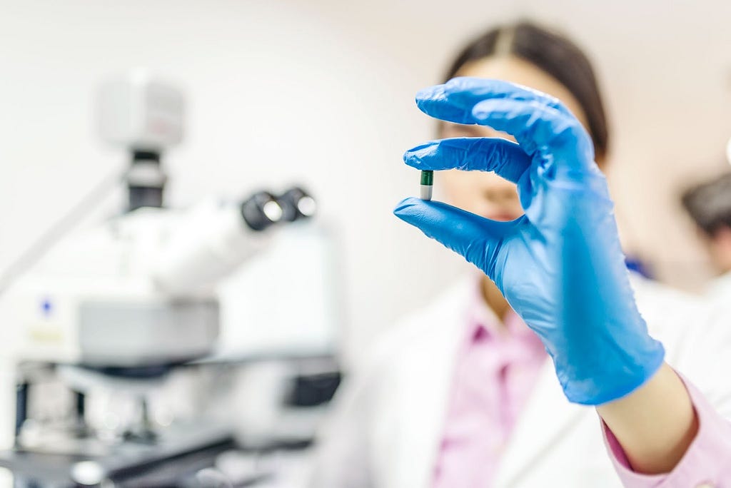 Young female scientist holding up a pill