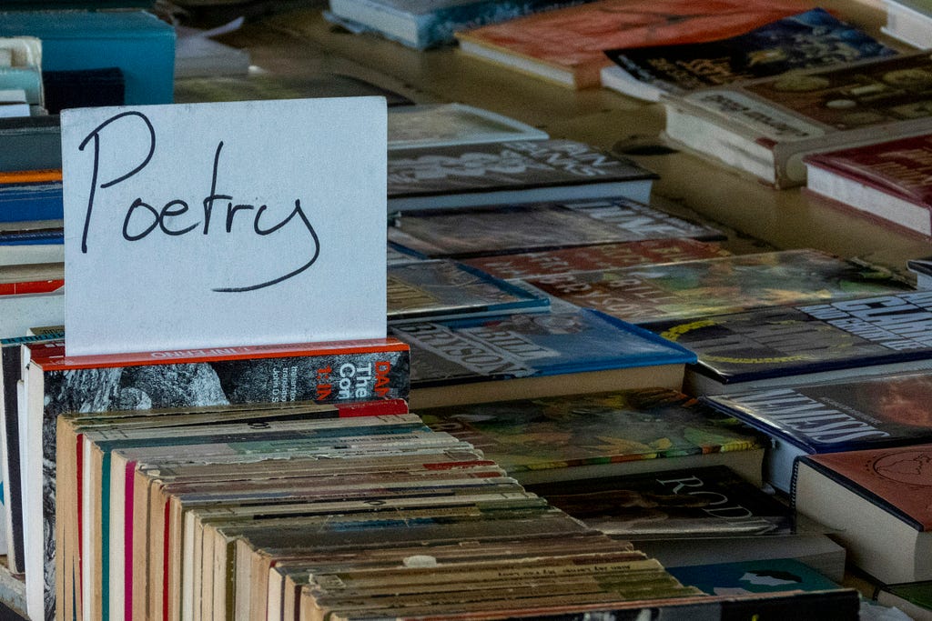 A handwritten sign reading poetry above a table of used books