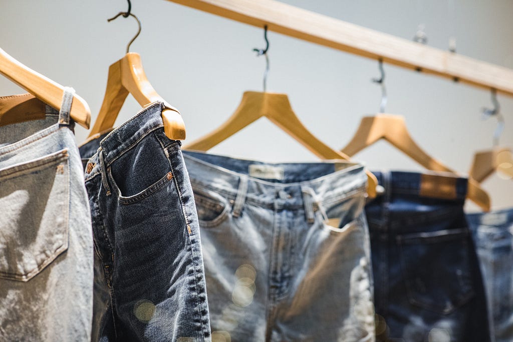 Several pairs of jeans on hangers.