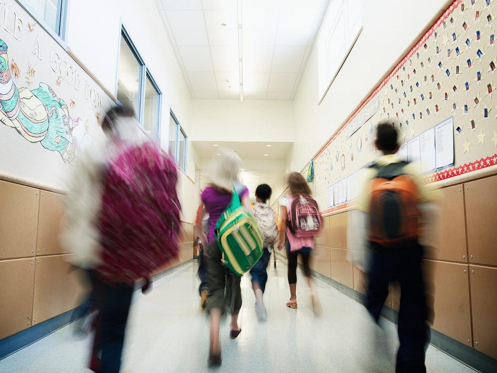 School hallway with blurred students walking away from the camera. Photo by Thomas Barwick/Getty Images