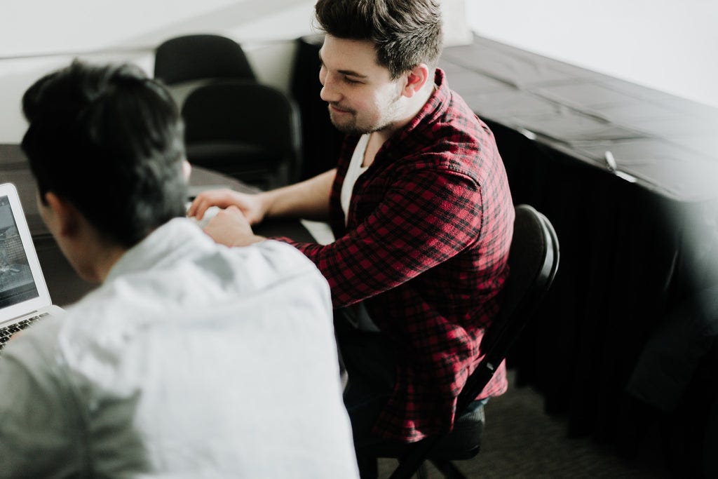 two men working together on a laptop