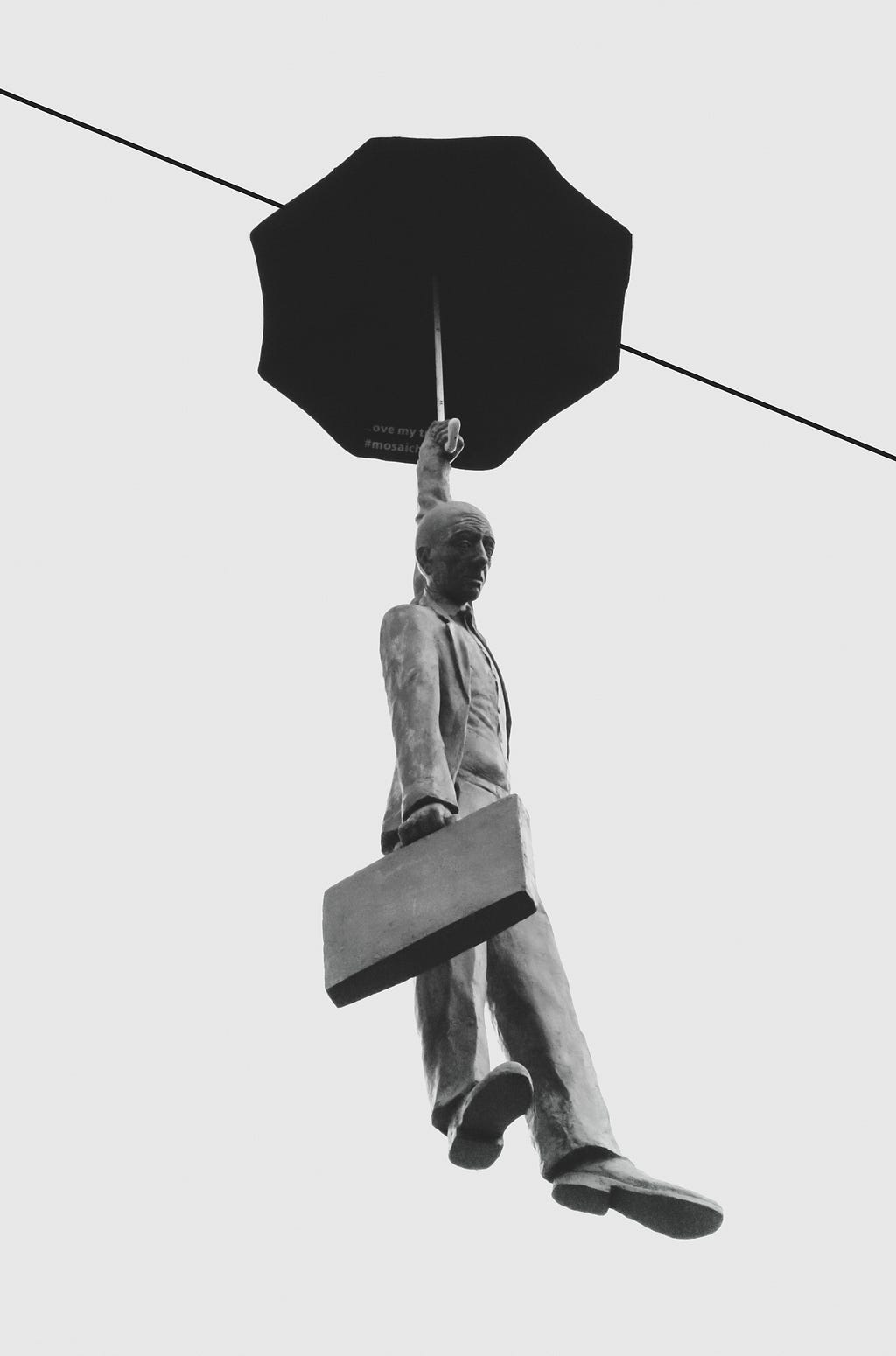Bleak sculpture of office worker carrying a briefcase and open umbrella