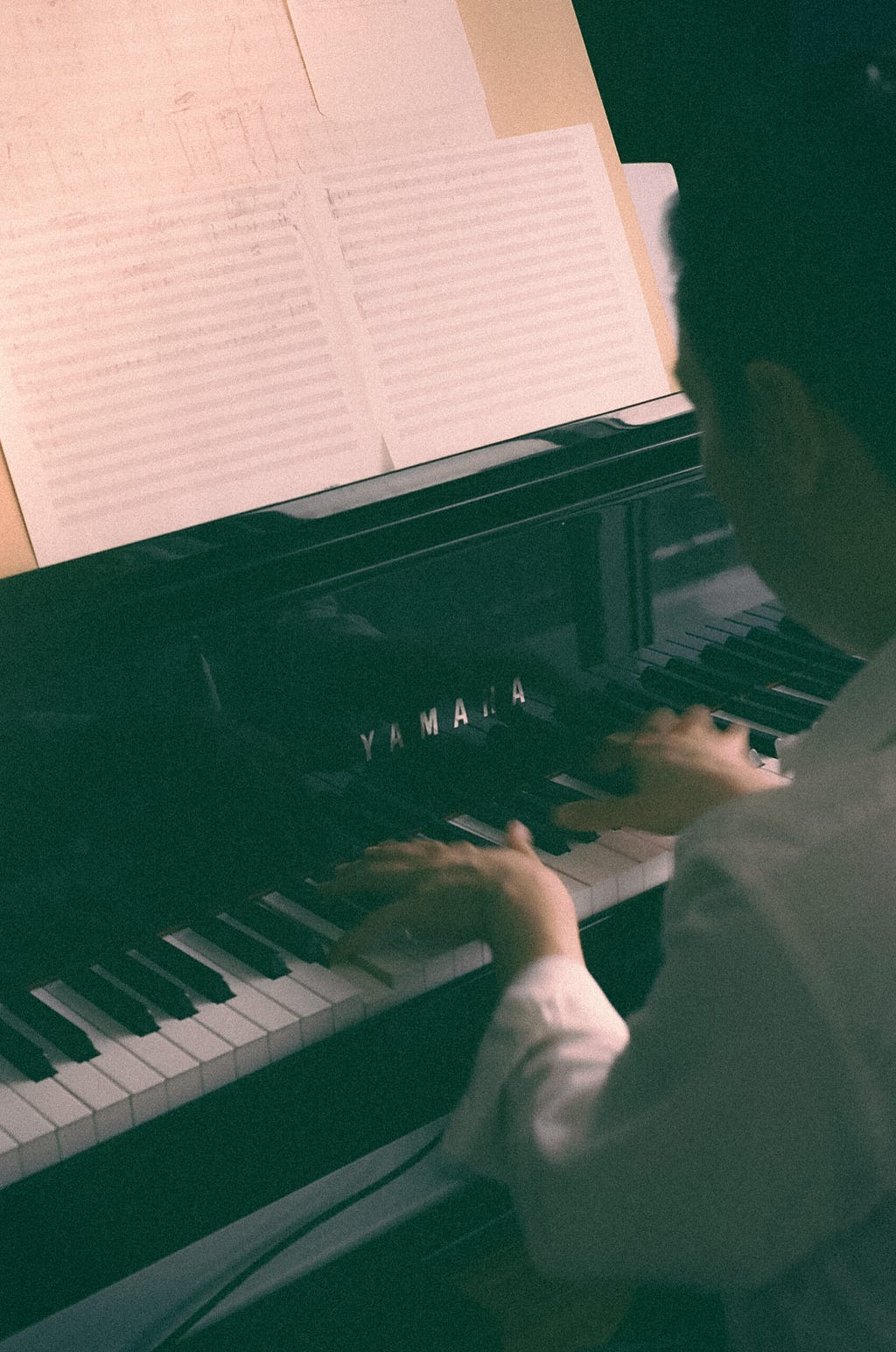 looking over man’s shoulder as he plays piano at home