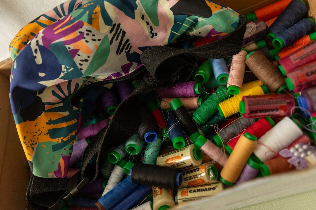 A bag filled with various spools of sewing threads.