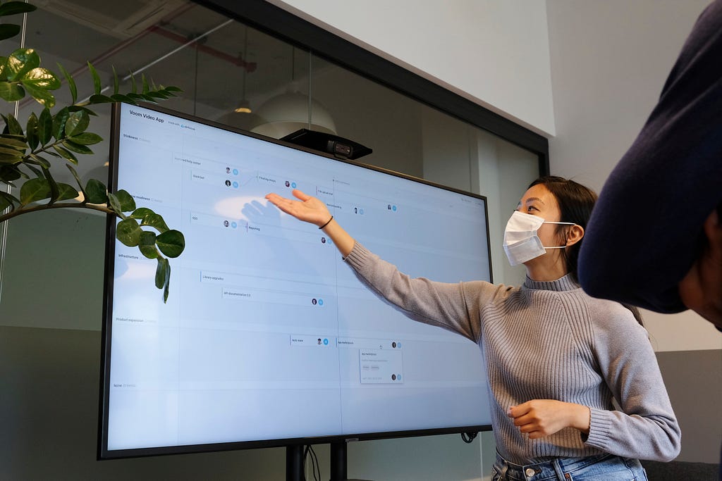 A masked woman giving a presentation