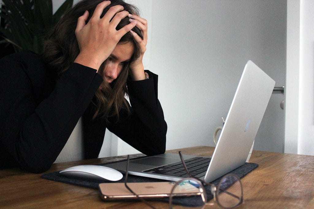 A woman with professional attire looking stress in front of a laptop