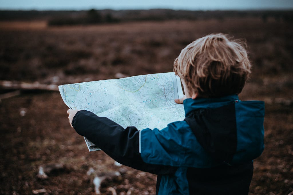 An image depicting a child looking at map for direction.