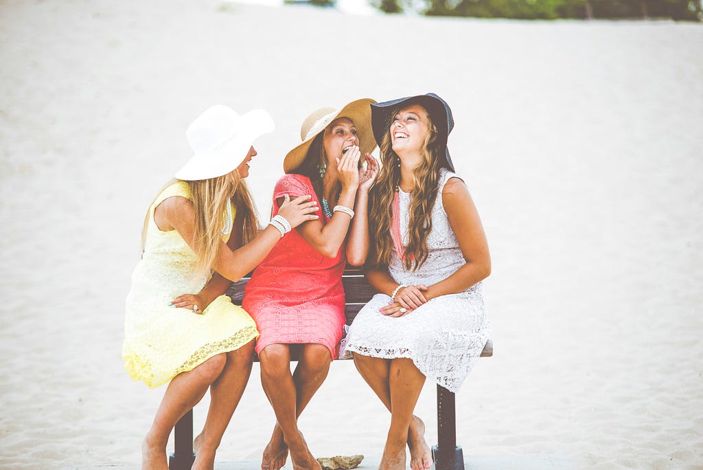 A trio of women sit laughing together.
