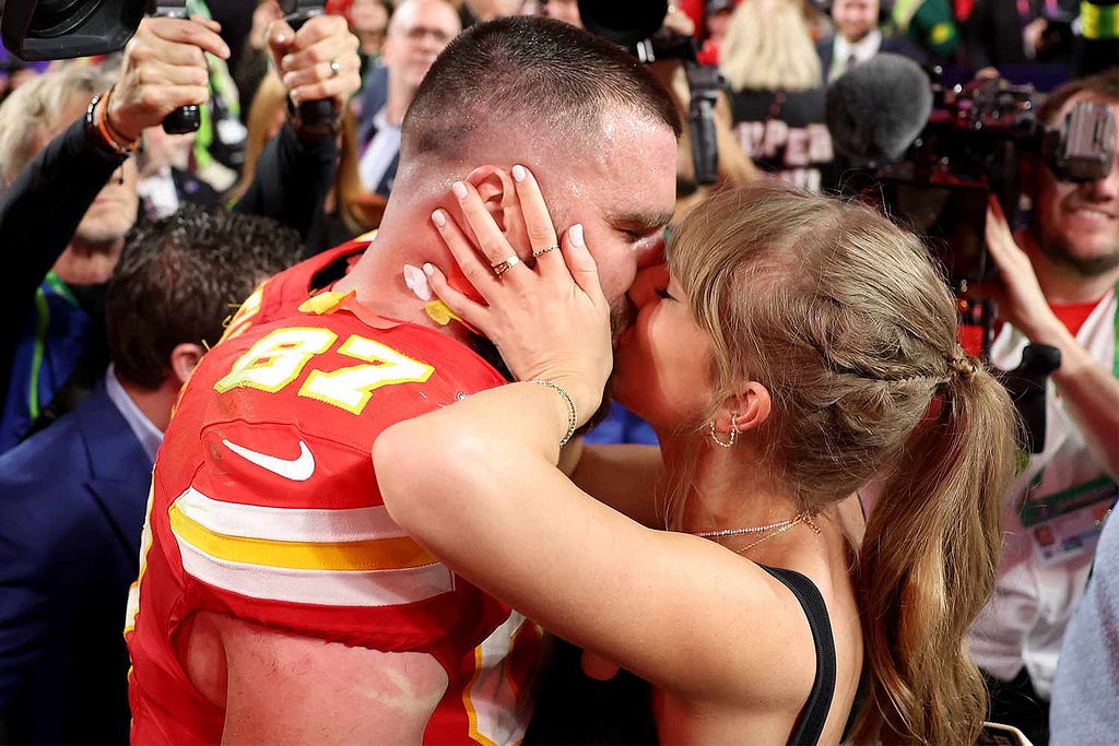 A Photo of Chief’s player Travis Kelce and girlfriend Taylor Swift sharing a kiss after he takes home super bowl win