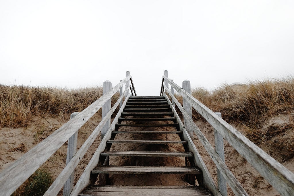 Wooden steps leading over a sand dune.
