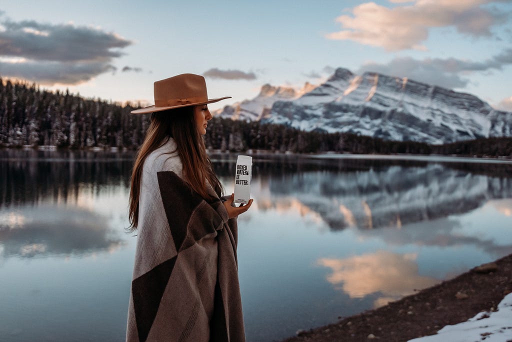 drinking boxed water by a snowy lake